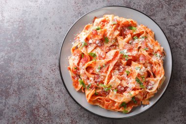 Pastırma ve domatesli pappardelle makarna üzerine parmesan peyniri serpiştirilmiş ve masaya yakın maydanoz dilimi serpiştirilmiş. Yukarıdan yatay üst görünüm