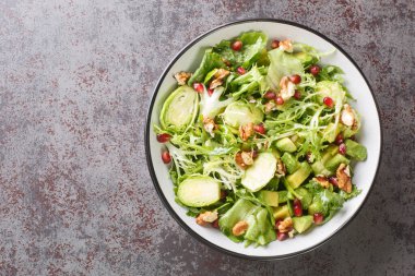 Sofrada Brüksel lahanası, avokado, lahana, marul, nar ve fındıklı diyet çiğ sebze salatası var. Yukarıdan yatay üst görünüm