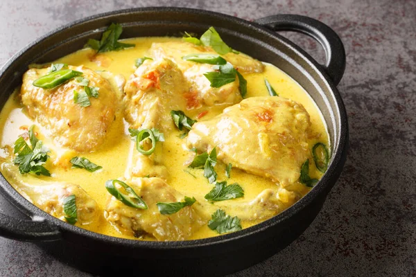 stock image Chicken pieces stewed in coconut sauce with spices, tomato, garlic, onion and chili pepper close-up in a frying pan on the table. horizonta