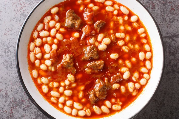 Turkish white bean stew with meat Etli kuru fasulye closeup in the plate on the table. Horizontal top view from abov