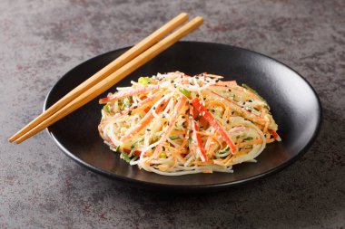 Yengeç eti ve jülyen sebzesinden yapılmış Kani salatası. Hepsi tatlı, baharatlı ve kremalı sosa batırılmış. Masanın üstünde. Yatay