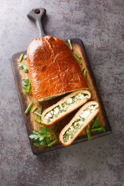 Haşlanmış yumurta, yeşil soğan, maydanoz, dereotu ve ıspanak ile doldurulmuş lezzetli turta masanın üzerinde. Yukarıdan dikey üst görünüm