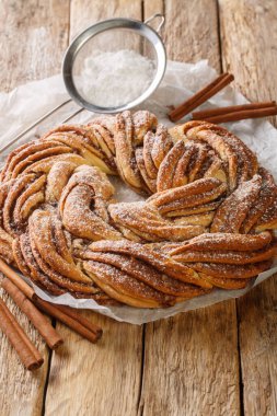 Kringle Lezzetli Brioche, şeker ve tarçınlı. Tahta masadaki kağıdın üzerine yakın plan. Dikey