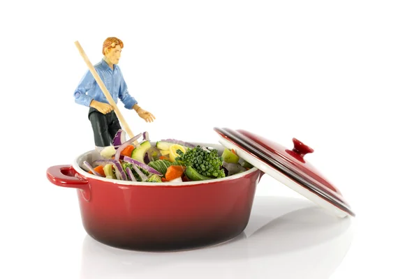 Muž míchání vegetariánské jídlo v červené pánev — Stock fotografie