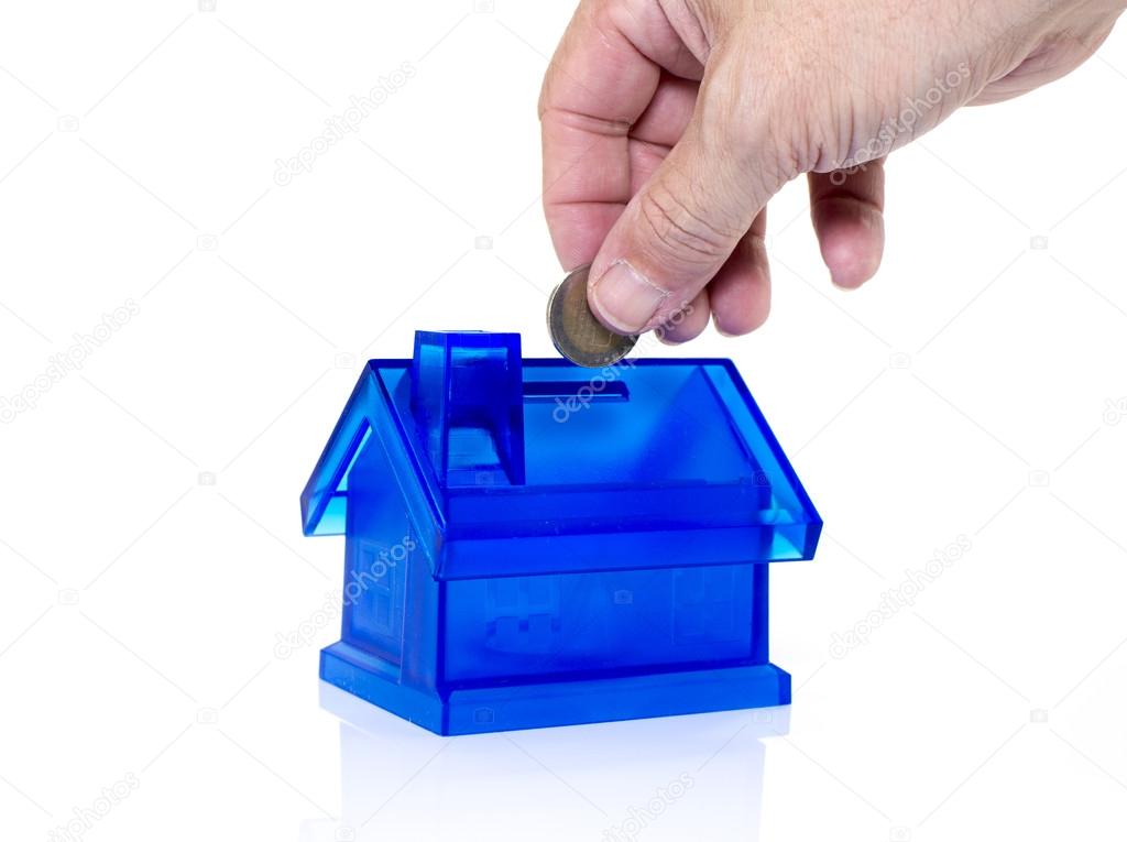 hand putting money in saving house