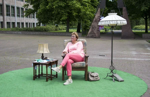 Mujer sentada en un parque en silla con mesa y lámpara — Foto de Stock