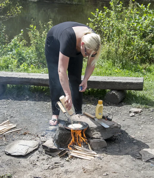 Woman making pancake on the campfire — Stock Photo, Image