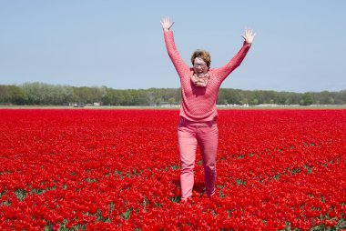 adult womanjumping in red tulip field clipart