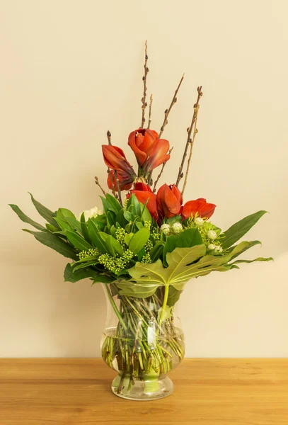 Vaso di vetro con Amarilli rossi e foglie verdi — Foto Stock