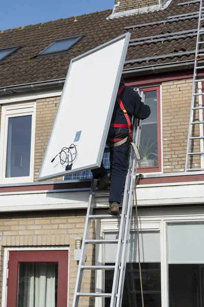 Man klättrar på stegen med solpanel — Stockfoto