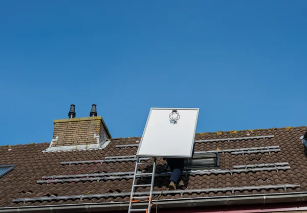 Man klättrar på stegen med solpanel — Stockfoto