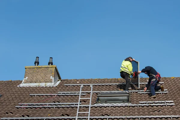 男人放在屋顶上的太阳能电池板 — 图库照片