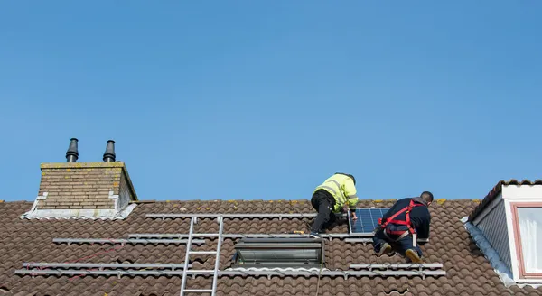 Hombre poniendo el panel solar en el techo — Foto de Stock