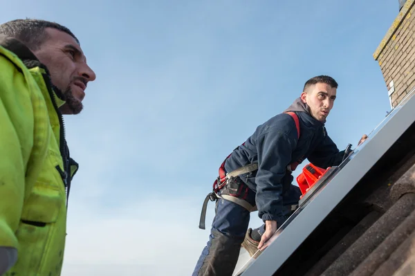 Людина кладе сонячну панель на дах — стокове фото