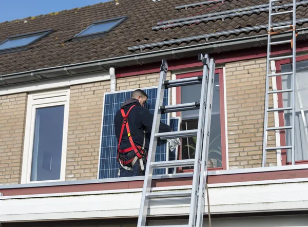 Man klimmen de ladder met zonnepaneel — Stockfoto