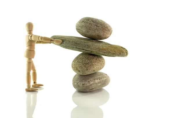 Wooden puppet holding rocks in perfect balance — Stock Photo, Image