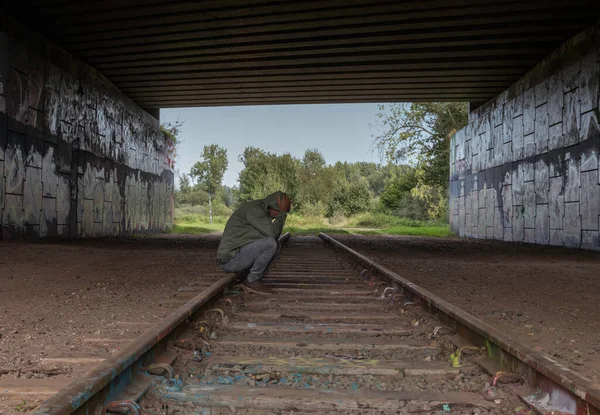 Человек, сидящий на железнодорожных путях — стоковое фото