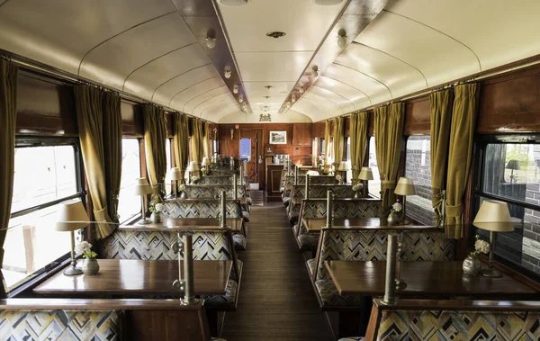 L'intérieur d'un ancien train avec des bancs, des tables et des lampes de table — Photo
