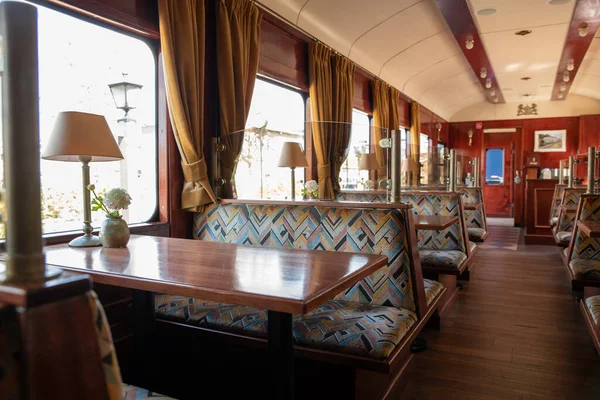 L'intérieur d'un ancien train avec des bancs, des tables et des lampes de table — Photo