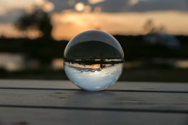 Sunset in a glass ball lying on a wooden table — Stock Photo, Image