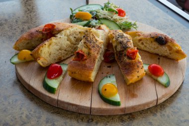 Ocaccia ekmeği, güneşte kurutulmuş domates ve salatalık bir restoranda tahta bir tahtanın üzerinde.