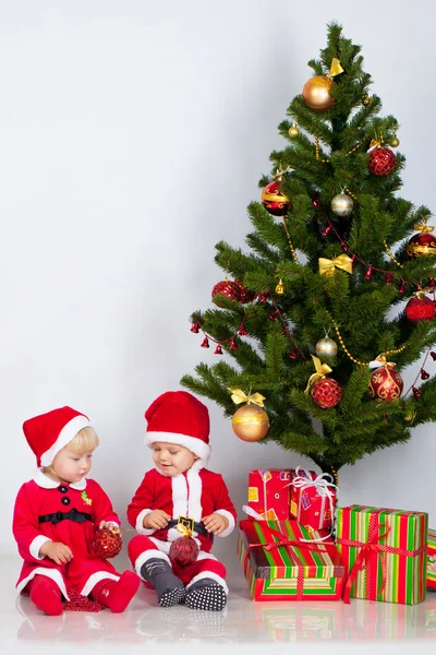 Two children under christmas pine — Stock Photo, Image