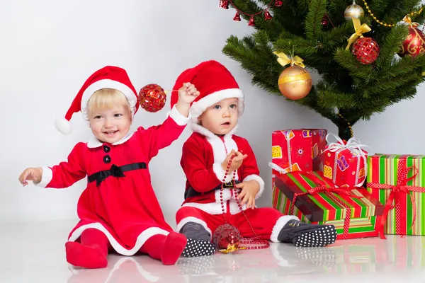 Two children under christmas pine — Stock Photo, Image