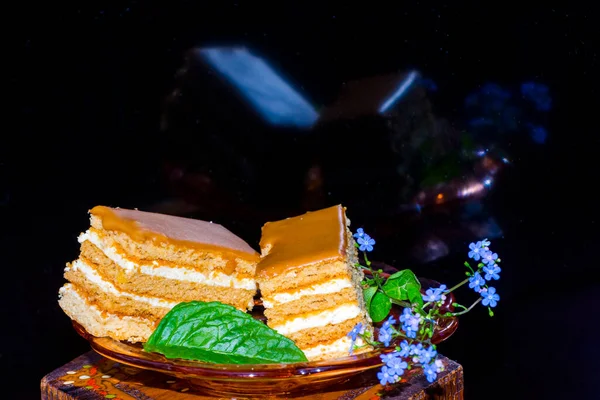 Honey cream cake on a small plate with mint leaf and flower