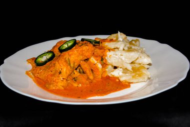 Beyaz tabakta erişteli yayın balığı güveci.