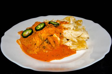 Beyaz tabakta erişteli yayın balığı güveci.