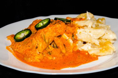 Beyaz tabakta erişteli yayın balığı güveci.