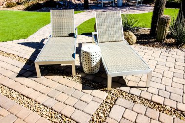 Arka bahçedeki kaldırımlara yaslanmış iki oturma odası sandalyesi