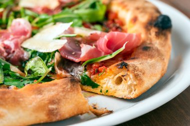Prosciutto Crudo, roket salatası ve parmesanlı lezzetli pizza.