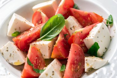Taze geleneksel caprese salatası mozarella, domates, zeytinyağı ve bitkilerle İtalyan aperatifleri. 