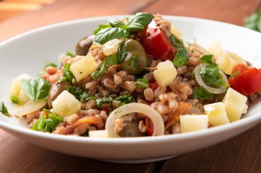 pearl barley with vegetables and basil on white plate