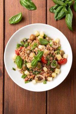 top view of pearl barley with vegetables and basil on white plate