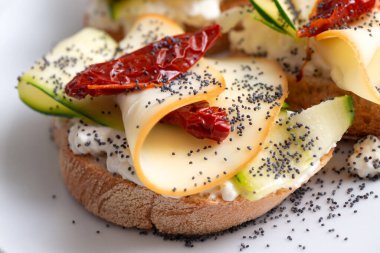 Füme peynirli sandviç, kurutulmuş domates ve dilimlenmiş salatalık.