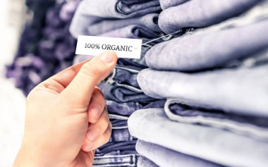 Organik kot pantolon, etik kot pantolon. Dükkandaki rafta bir yığın kıyafet var. Etiketle ve etiketle. Sürdürülebilir perakende moda ve doğal kumaş ve tekstil ürünü. Müşteri pantolon alıyor..