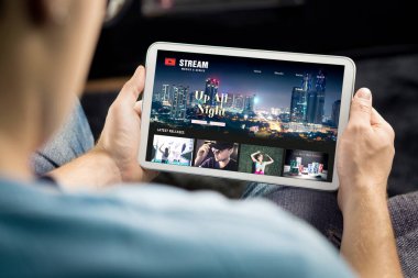 Tabletteki film ve dizi VOD hizmeti. İnternetten talep dizisi ya da film izlemek. Abonelik medya kataloğundan video eğlencesi seçen bir adam. Yayınlanan web sitesi kitaplığı modeli.
