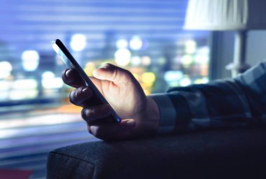 Dolandırıcılık mesajlı telefon, bilinmeyen dolandırıcılık çağrısı ya da gece mesajlaşması. Akıllı telefon kullanan bir adam. İsimsiz arayan ya da SMS dolandırıcısı. Gizli buluşmalarla aldatan. Karanlık evdeki cep telefonu ekranından gelen ışık.