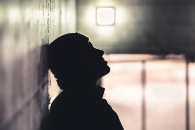 Karanlıktaki ciddi üzgün adam. Depresyondaki endişeli kişi travma, yalnızlık ya da uyuşturucu bağımlılığından muzdarip. Yanlışlıkla utanç üstüne utanç içinde evsiz bir serseri. Hüzünlü, hüzünlü ve hüzünlü dramatik bir siluet..