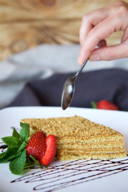 Yakın plan tatlı bir parça kek ya da kremalı puf kektir. Yiyecek taze meyve, çilek ve yeşil nane yapraklarıyla süslenmiş. Şekerleme kavramı