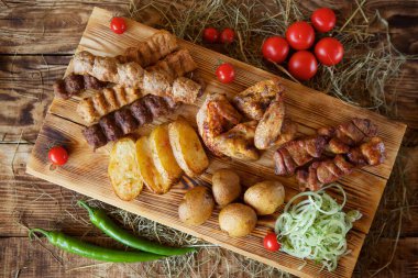 Izgarada pişirilmiş et, sebze ve mantarlar ahşap kesim tahtasının üzerinde yatıyor. Geniş bir grup Diner 'a ayarlayın. Restoranlar ve kafeler için menü kavramı.
