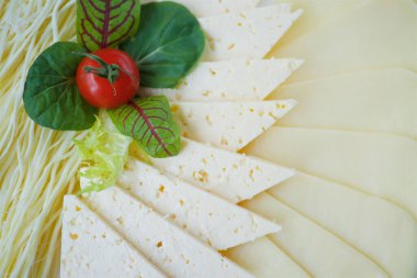 Yeşillikle süslenmiş beyaz bir tabakta dilimlenmiş peynir..