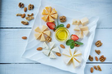 Beyaz bir tabakta bal ve meyve dilimlenmiş peynir..