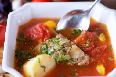 Restorandaki masada etli, patatesli ve sebzeli lezzetli çorba. Ekmek, domates, sarımsak ve fesleğen. Yemek ve restoran menüsü.