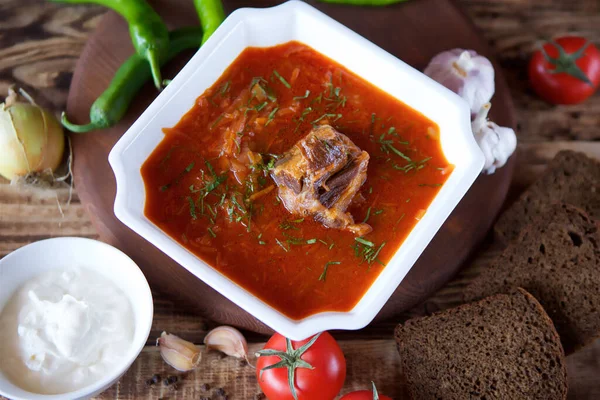 Restorandaki masada biftekli leziz zengin borş var. Arkaplanda siyah ekmek, acı biber, kiraz domates ve sarımsak var. Yemek ve restoran menüsü.