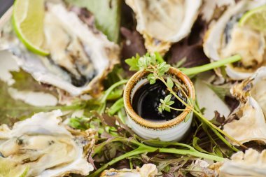 Limon dilimleri, soya sosu ve otlarla süslenmiş kabuklu fırında pişmiş istiridye. Restoran yemekleri şeften..