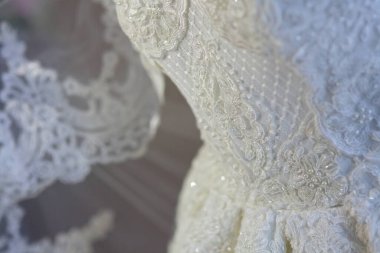 Dantelli ve nakışlı, kumaştan gelinliklerle süslenmiş.