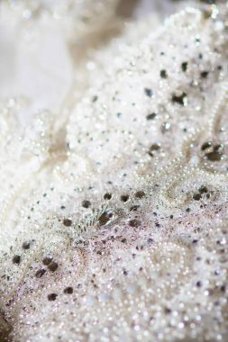 Dantelli ve nakışlı, kumaştan gelinliklerle süslenmiş.